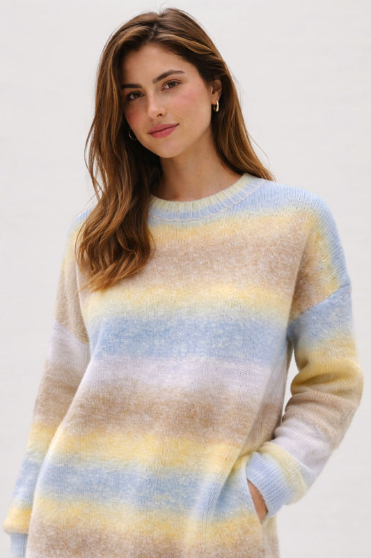 Woman wearing a striped sweater with pastel colors on a plain background