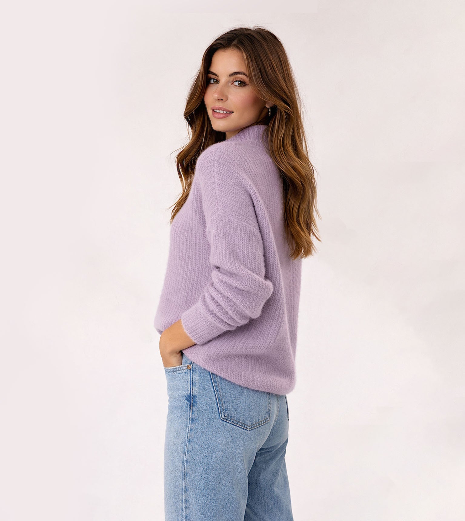 Woman wearing a light purple sweater and blue jeans on a white background