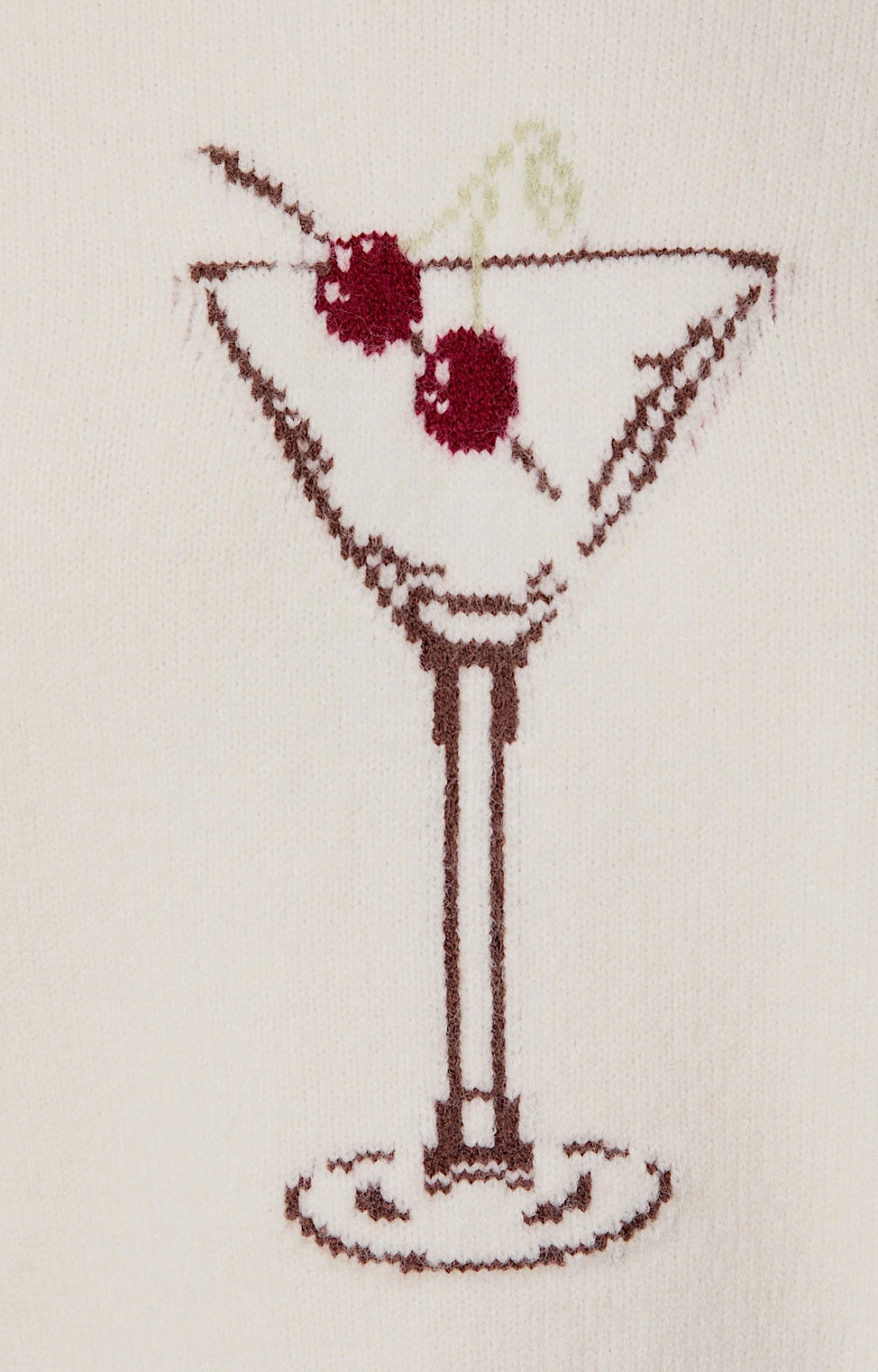 Cross-stitched martini glass with olives on a beige background