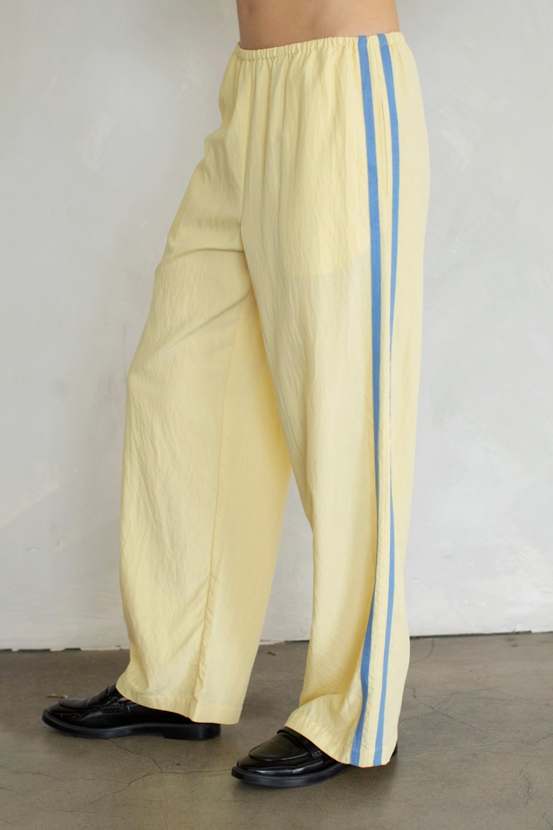 Yellow pants with blue stripes worn by a person against a plain background